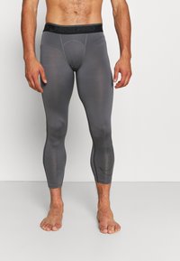 Leggings Nike Pro grises con un diseño ajustado, costuras planas y una cinturilla ancha negra con el logo. Tela suave y elástica para mayor comodidad.