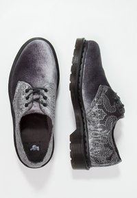 Chaussures en velours gris à lacets avec des motifs floraux brodés et de semelles noires épaisses, présentées de dessus et de côté sur un fond blanc.
