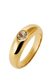 Anillo de oro con una superficie lisa y pulida que presenta un diamante redondo de color marrón claro engastado en un bisel circular.