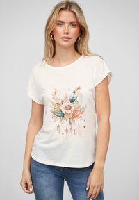 T-shirt en coton blanc avec un graphique floral et de plumes dans des couleurs pastel douces. Encolure ronde et manches courtes repliées. Coupe décontractée.