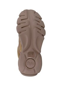 Sole of a sneaker featuring a textured, rubber material in light beige, with a distinctive tread pattern and logo detail in the center.
