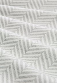 Gepolsterter Stoff in Grau und Weiß mit einem Zickzackmuster. Weiche Textur mit abwechselnden Streifen. Glattes und geschichtetes Erscheinungsbild.