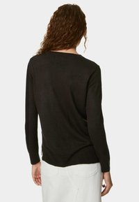 Maglione nero a maglia con vestibilità morbida, maniche lunghe e scollatura rotonda. Orlo posteriore leggermente più lungo con spacco laterale. Texture liscia.