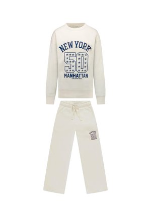 Set van sweatvest en broek in crèmekleur met "New York 50 Manhattan" blauwe tekst en sterdetails op de borst en linker broekspijp.