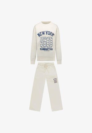 Set van sweatvest en broek in crèmekleur met "New York 50 Manhattan" blauwe tekst en sterdetails op de borst en linker broekspijp.