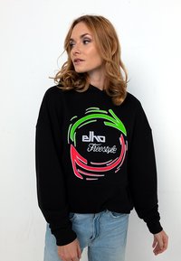 Schwarzer Kapuzenpullover mit einem kreisförmigen grafischen Design in Neon-Grün, Pink und Weiß sowie dem Text "elko Freestyle". Hergestellt aus weichem Material.