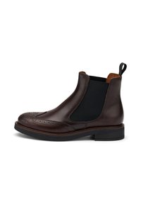 Botín Chelsea de cuero marrón con detalles de brogue, paneles laterales elásticos y un lazo para tirar. Suela gruesa con un leve tacón. Acabado suave.