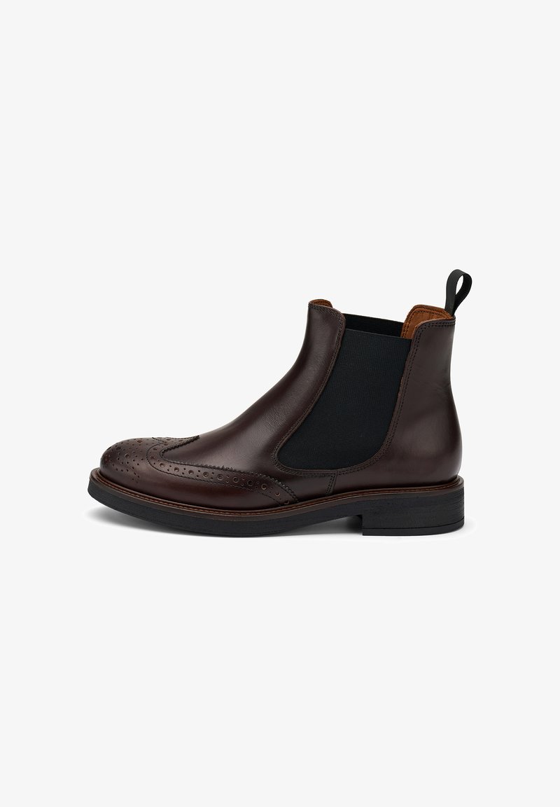 Botín Chelsea de cuero marrón con detalles de brogue, paneles laterales elásticos y un lazo para tirar. Suela gruesa con un leve tacón. Acabado suave.