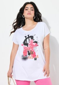T-shirt a maniche corte bianco con un grafico di un cane a palloncino rosa, macchie nere e accenti testuali colorati. Tessuto di cotone liscio, vestibilità comoda.