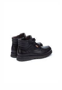 Bottines en cuir noir avec un bout arrondi, col rembourré, laçage sur le devant et semelle en caoutchouc texturée pour l'adhérence. Détails de couture notables sur les côtés.