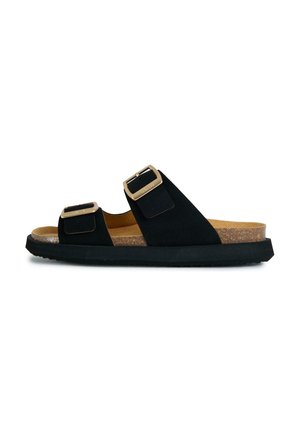 Black slip-on sandal with cork footbed, two adjustable straps with gold-tone buckles, and black rubber sole shown in side view.