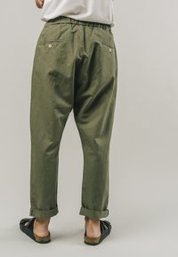 Olivově zelené kalhoty volného střihu s elastickým pasem, dvěma zadními kapsami a ohrnutými manžetami. Vyrobeny z lehké, jemné tkaniny.