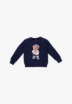 Navy blue sweatshirt featuring a bear graphic in a white shirt with a red "SUPER" print, wearing gray shorts and black sneakers.