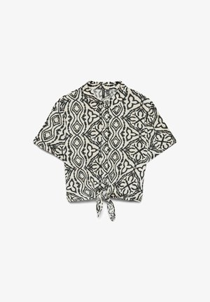 Chemise courte en noir et blanc avec un nœud à l'avant, présentant un motif géométrique abstrait. Confectionnée en tissu léger avec des manches courtes.