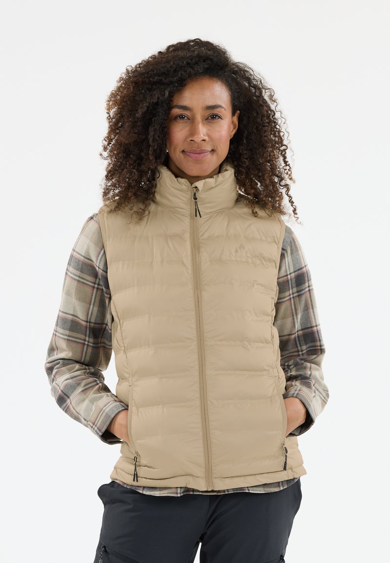 Beige pufferväst med hög krage, dragkedja framtill och sidofickor, över en rutigt långärmad skjorta i grå, grön och röd nyanser.