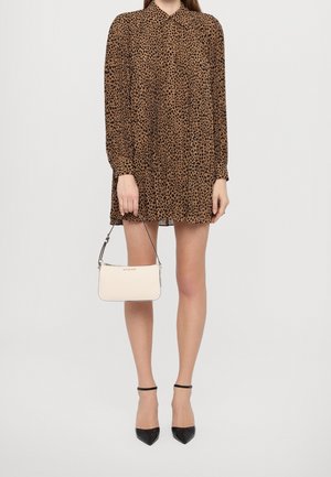 Langärmeliges Kleid mit Leopardenmuster und Kragen; kombiniert mit einer kleinen weißen Handtasche und schwarzen spitzen High Heels mit Knöchelriemen.