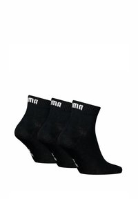 Calcetines negros hasta el tobillo con puño acanalado, que presentan el logo blanco de "PUMA". Textura suave, diseñados para la comodidad. Tres pares en el conjunto.