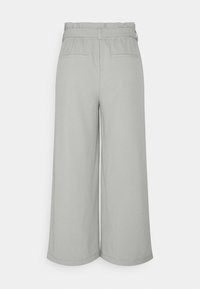 Pantalon large gris clair avec taille élastiquée, passants pour ceinture et deux poches passepoilées à l'arrière.