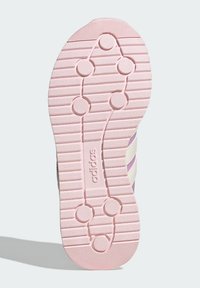 Rosa gummisula med texturerade gropar och cirkulära grepp. Har vita och lavendelfärgade ränder längs sidorna, med varumärkeslogotyp synlig.