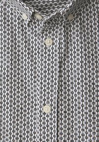 Camisa de botones con un patrón geométrico en blanco y negro, fabricada en algodón, con cuello corto y botones en forma de perla.