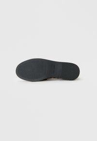 Black rubber sole with textured grip pattern, featuring a smooth heel section and curved edges. Designed for traction and durability.