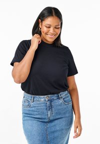 T-shirt di cotone nero con maniche corte, indossato con una gonna a matita in denim azzurro chiaro con chiusura a bottoni e tasche laterali.