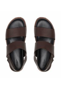 Brown leather sandals with two wide straps, open toe design, and a textured black sole. Features stitching accents and a comfortable fit.