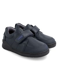 Zapatos de piel azul marino con una correa de velcro, punta redondeada, cuello acolchado y suela de goma negra texturizada. Presentan acentos de costura visibles.