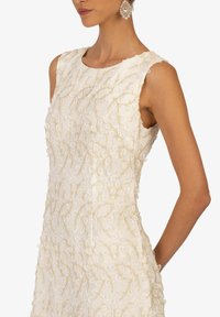 Ärmelloses weißes Kleid mit kunstvollen goldenen Stickereien, runder Ausschnitt, taillierte Silhouette und seitlichen Taschen für zusätzliche Funktionalität.