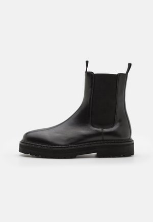 Schwarze Leder-Chelsea-Boots mit elastischen Seitenpaneelen, runder Zehenform, chunky schwarzer Sohle und Zuglaschen am Knöchel für einfaches An- und Ausziehen.