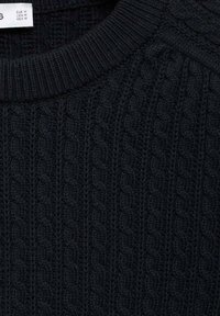 Suéter negro de punto con un patrón de trenzas texturizado, cuello redondo acanalado y tela suave. Etiqueta de cuidado visible en la parte superior.
