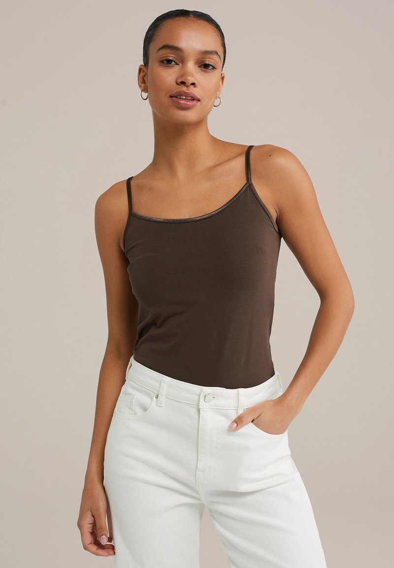Barna, testhez simuló camisole vékony pántokkal, kerek nyakkivágással, magas derekú fehér farmernadrággal párosítva. Sima anyagú kivitel.