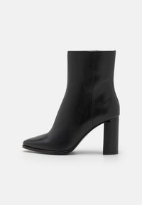 Stivale alla caviglia in pelle nera con punta affilata e tacco geometrico a blocco, caratterizzato da una superficie liscia e un design pulito e minimalista.