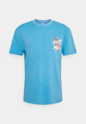 Camiseta de algodón azul claro con cuello redondo, mangas cortas y un diseño de loro impreso en el lado izquierdo del pecho. Textura suave y ajuste casual.