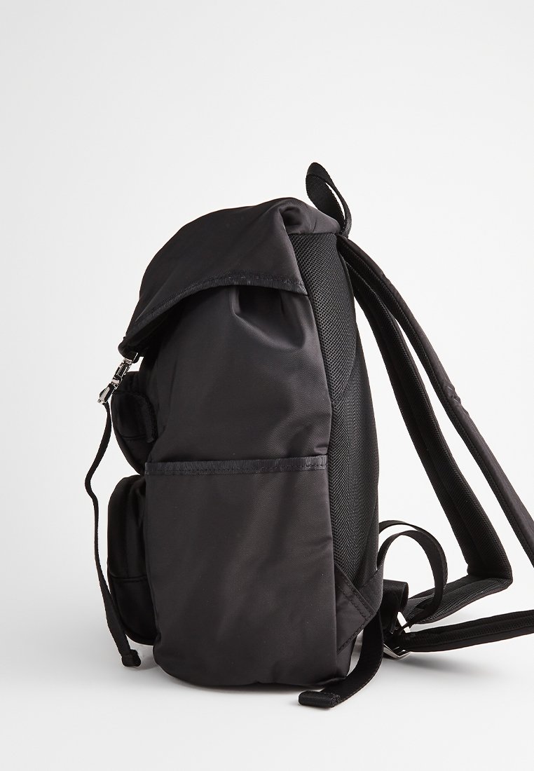 Czarny nylonowy plecak z wyściełanymi paskami, przednią kieszenią na zamek błyskawiczny i zamknięciem na klapę u góry, pokazany z boku.