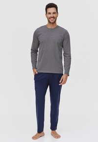 Męski zestaw piżamowy składający się z wzorzystej, czarno-białej bluzki z długim rękawem oraz jednolitych granatowych spodni. Wygodne dopasowanie, miękki materiał.