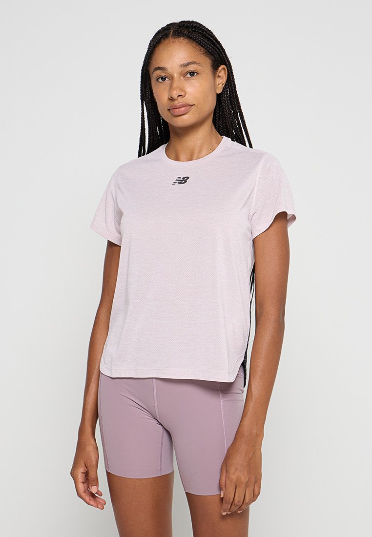 Camiseta deportiva de color rosa claro con mangas cortas y cuello redondo, que presenta un pequeño logotipo negro en el pecho y un corte relajado.