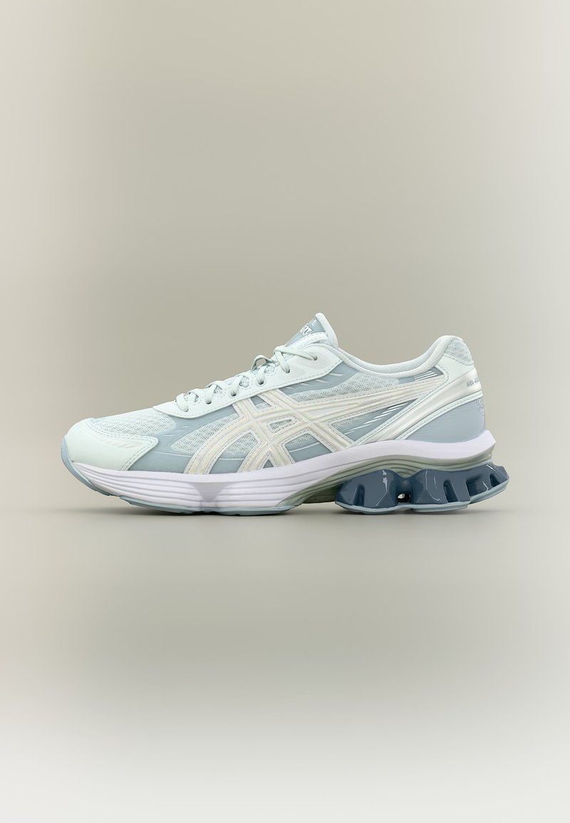 Chaussure de course gris clair et blanche avec dessus en mesh et design distinctif de semelle segmentée sur un fond uni.