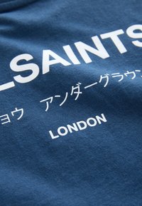 Niebieska bawełniana koszulka z białym napisem "ALL-SAINTS LONDON" oraz dodatkowym tekstem w alfabecie niezachodnim. Miękka w dotyku, casualowy design.