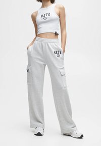 Helles graues Crop-Top mit "Nets"-Logo und passenden, locker sitzenden Sweatpants mit seitlichen Taschen und elastischem Bund.