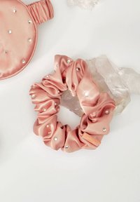 Chouchou en satin rose froncé orné de petites gemmes argentées, mettant en valeur sa texture lisse et son éclat subtil.