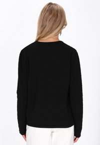 Pulover negru cu mânecă lungă, realizat dintr-un material texturat. Are un decolteu rotund și un design neted în spate, cu detalii subtile pe mâneci.