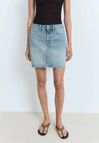 Denim mini krilo v svetlo modri barvi z ravnim krojem, sprednjimi žepi in zadrgo. Združeno z črnimi japankami z okrasnim trakom.