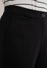 Černé kalhoty na míru s elegantním designem, včetně čistého pásku, předních kapes a jednoho knoflíku na zapínání. Hladký povrch látky.