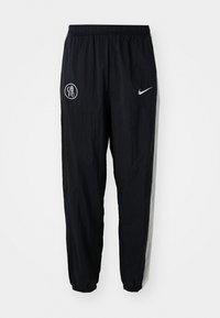 Black nylon track pants featuring an elastic waistband, tapered cuffs, a white Nike logo, and a Chelsea FC emblem on the front.