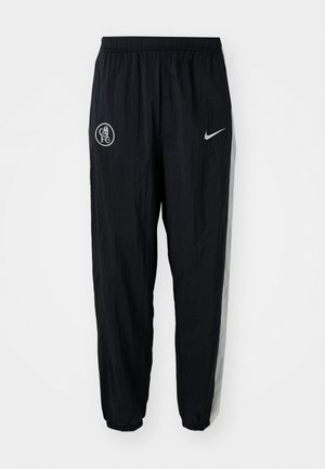 Black nylon track pants featuring an elastic waistband, tapered cuffs, a white Nike logo, and a Chelsea FC emblem on the front.