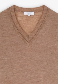 Suéter marrón de cuello en V hecho de un suave tejido de punto con una sutil textura. Presenta bordes acanalados y una etiqueta en el cuello.