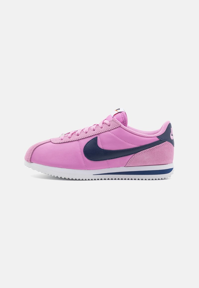 Pink athletic shoes with a suede and smooth upper, featuring a dark blue swoosh, white midsole, and patterned rubber sole.