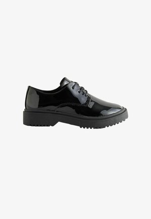 Zapato negro de cordones de cuero brillante con suela gruesa texturizada, tacón bajo y puntera redonda, de perfil sobre fondo blanco.