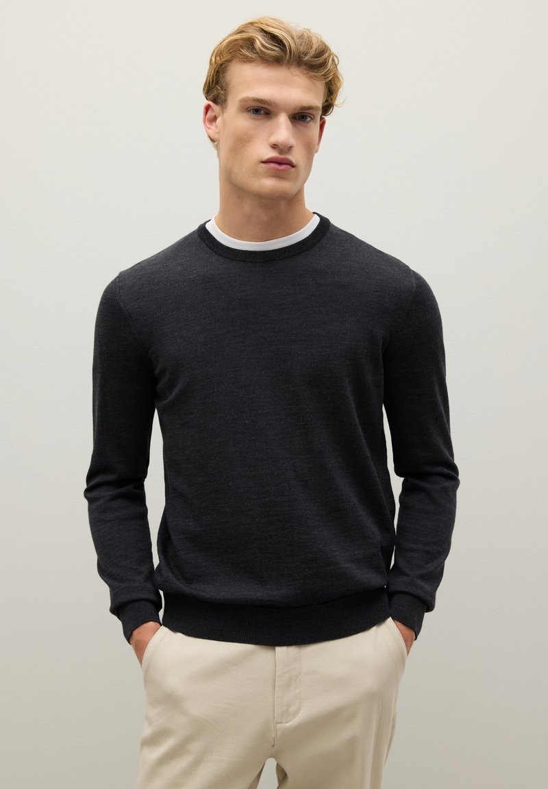 Maglione grigio scuro con maniche lunghe e scollatura a girocollo, caratterizzato da un colletto e polsini a coste. Tessuto morbido con un design aderente.